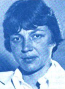 A white woman with short dark hair cut in bangs, wearing a white collared shirt; photo is printed in blue ink in original source