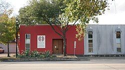 The front of a red building partially obscured by trees.