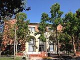 An exterior shot of a red brick building behind several trees.