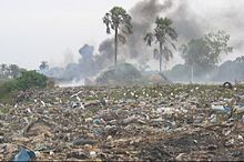 A dumpsite with smoke coming from it.