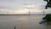 Large waterway, with small boats in the foreground and a long bridge in the background