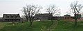 Three trees in foreground on cut grass, farmhouse-style buildings across background