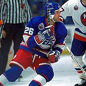 Two hockey players on the ice and a referee in the background