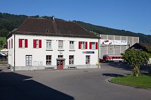 Three-story building with white walls and a dark, arched roof