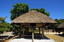 A small wooden storehouse atop large wooden pole supports