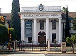 White building with the inscription Navy school of mechanics in Spanish