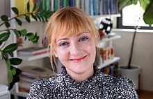 Artist Kelli Anderson in front of a row of colorful books