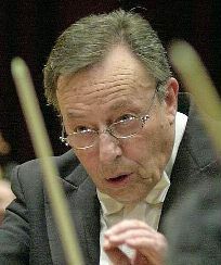 Orchestral conductor, hard at work with passionate expression: clean-shaven man with greying hair and spectacles