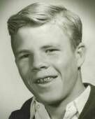 A black and white photograph of a smiling teen boy with braces