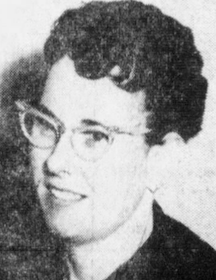 A young white woman with short dark curly hair, wearing cat-eye glasses