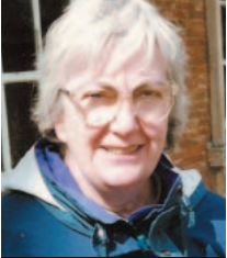 grey-haired woman wearing glasses and a teal coat