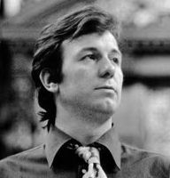 Young man with longish dark hair, patterned tie and dark shirt