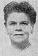 A photograph of a middle-aged white woman with short dark hair. She is wearing pearls.