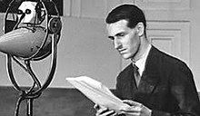 young man standing by a large 1930s microphone