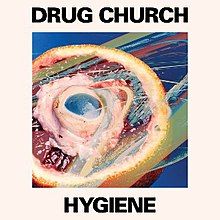 A beige square with a picture of an orange cut in half with a mitochondria model within the orange. Above the image reads "DRUG CHURCH" in black, all capital letters. Beneath the image reads "HYGIENE" in black, all capital letters.