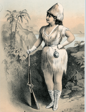 moderately buxom white woman standing, holding a rifle and wearing a costume intended to suggest a castaway