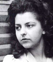 Black and white glamour portrait of young woman with long, dark, curly hair brushed back, and serious expression