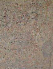 An eroded painting in the caves showing a man dancing and holding a trident-like staff