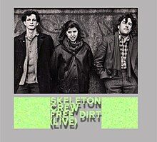 A black-and-white photograph of Tom Cora, Zeena Parkins and Fred Frith standing next to each other in front of a wall with the lettering "Skeleton Crew Free Dirt (Live)" below it