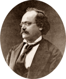 photograph of middle-aged white man with receding dark hair, spectacles and moustache, in semi-profile, facing right