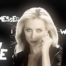 Brit Smith with her hand clenched in front of her face. Various words from the lyrics are written in white on the black background.