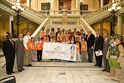 Governor Perdue, GEMA director Charlie English, ReadyKids mascot Rex the mountain lion, and Georgia elementary school students pose with a banner at Ready Georgia's official launch