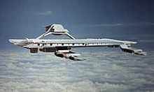 An airborne structure resembling a seagoing aircraft carrier, hovering at high altitude above clouds