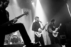 Three men are on stage playing guitars.