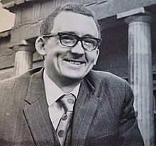 Allen Butterworth, smiling and wearing a suit, is stood outside of the Yorkshire Museum