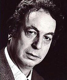 Black and white publicity headshot of clean-shaven man, with short, curly, tousled hair, strong features and a serious expression