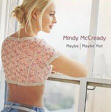 A woman with blonde hair and a pink crop top is staring outside a window. On the right of her is MINDY MCCREADY, typed in pink, Below that is MAYBE / MAYBE NOT, typed in black.