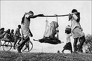 Two Muslim men (in a rural refugee train headed towards Pakistan) carrying an old woman in a makeshift doli or palanquin of 1947.