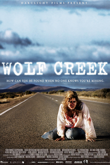 A woman sitting on a deserted highway, her white shirt is stained with patches of blood