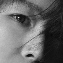 A grey-scale close-up shot of Ai's face with her bangs covering her left eye.